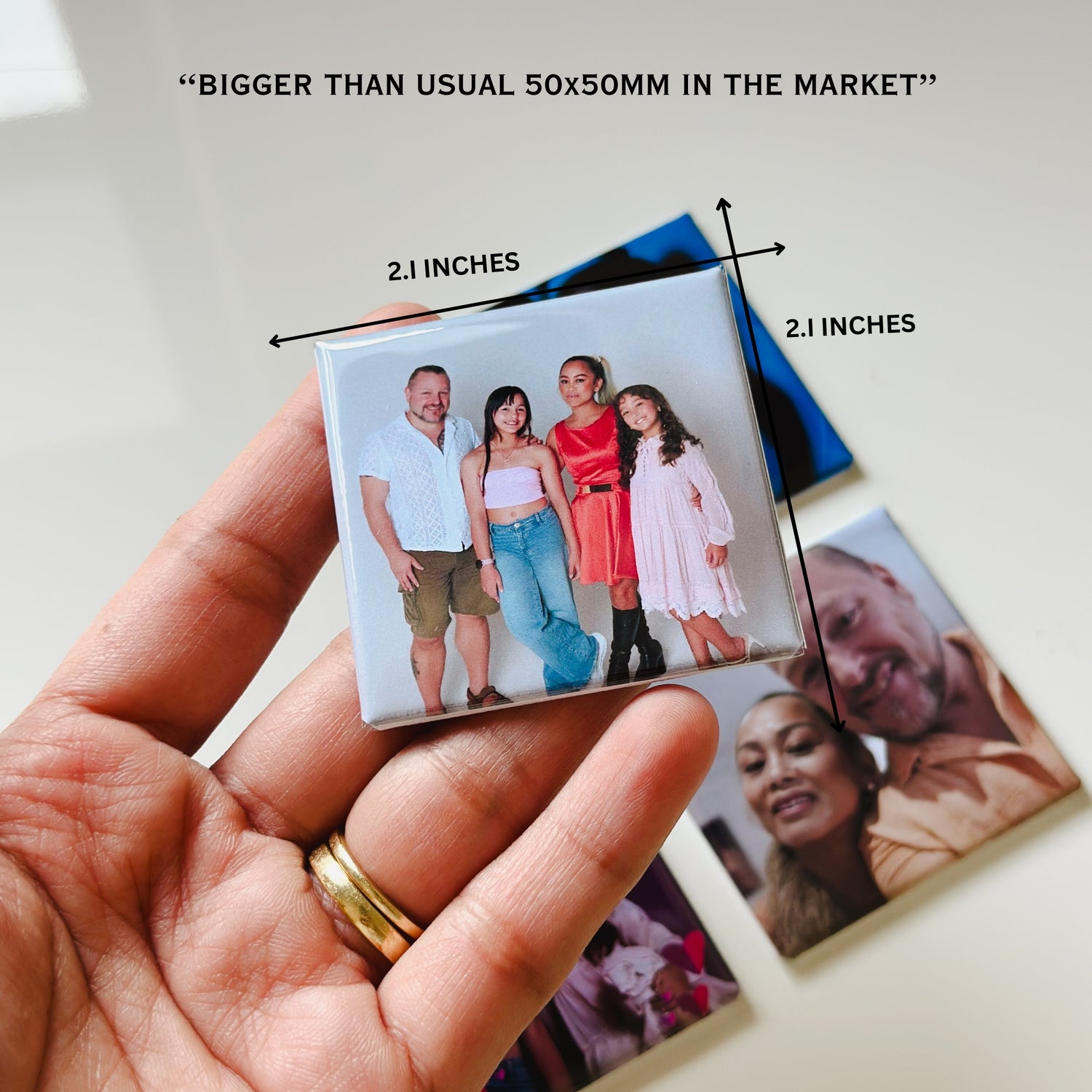 Hand holding a small photo magnet with family portrait, showing its size compared to a 50x50mm magnet.