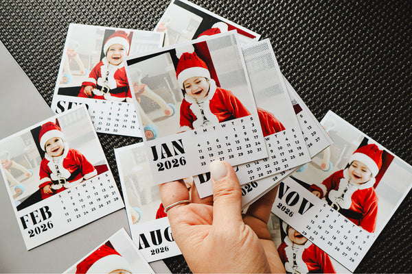 Calendar with a baby in a Santa hat held by a hand on a textured surface