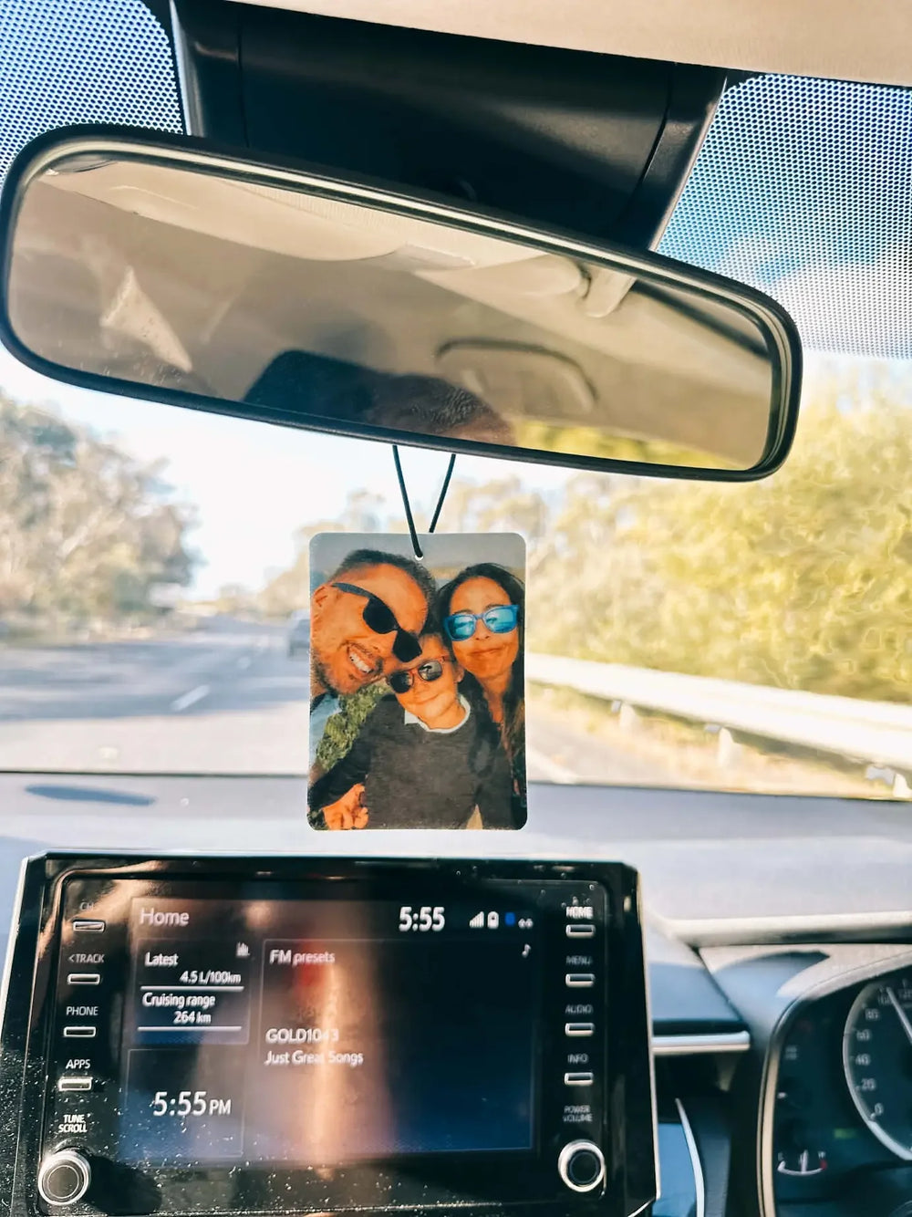 A photo air freshener hanging from a car mirror